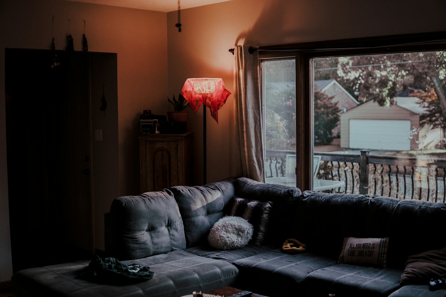 Grey sectional sofa with pillows near a lamp and window.