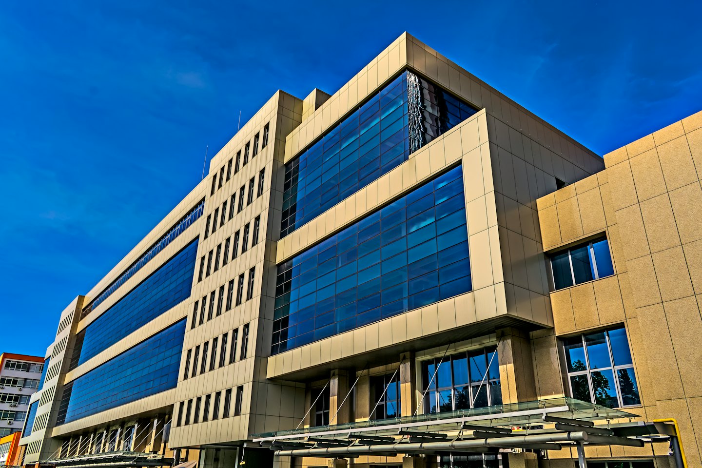 Modern corporate building with tan panels and reflective glass windows.